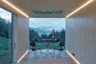 The birch-clad interior frames views of the outside settings. Strip lights along the exterior walls provide directional focus outward.