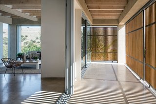 The main living spaces open directly onto a grand exterior patio shaded by wooden screens.