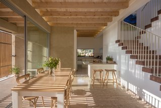 Light stone paving and wooden beams run continuously from interior to exterior, further blurring the boundary between the two.
