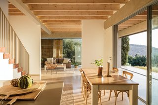 Exposed wooden beams draw in the natural elements. Furnishings and textiles are composed of similar materials, creating a subdued and relaxed interior palette.