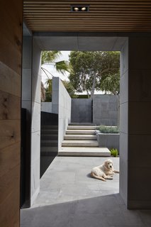 Natural stonework flawlessly transitions from the exterior landscaping elements to the home's facade, creating a pure, architectural gem. 