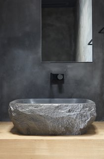 A custom wash basin from the stone supplier BAMSTONE emphasizes the home's connection to natural materials and the environment.