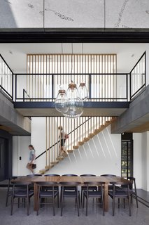 Vertical wood slats continue from the stair treads to the ceiling, emphasizing the openness and grandeur of the open, two-story dining space.