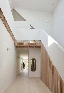 Douglas fir wooden slats follow the slope of the stairs and continuously wrap around as a guardrail, drawing the eye up and around.