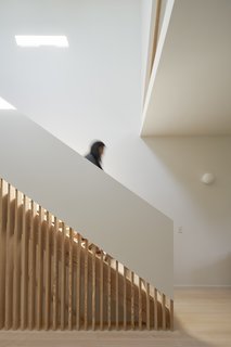 By incorporating wood slats into the stair wall, light from above is able to pass farther into the space between levels.