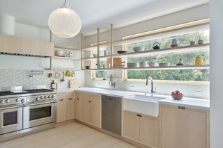 Customized whitewashed woodwork with Caesarstone Fresh Concrete counters and a geometric Health Tile Little Diamond backsplash carry the neutral palette from the atrium into the kitchen. A Mooi pendant adds a nice subtle accent.