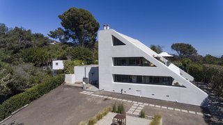 The triangular shape is emblematic of futuristic architecture. Ribbons of glass break away from the white concrete exterior.