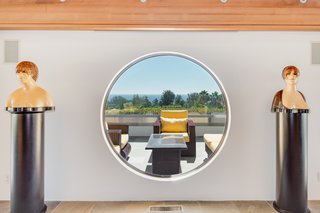 Dramatic windows—including circular shapes—frame scenic ocean views.