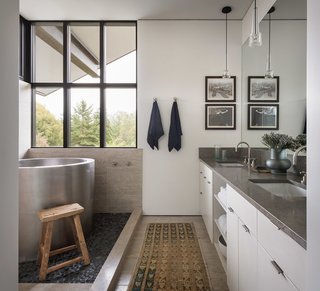 The bath areas continue the natural, simple material palette. A large soaking tub sits atop pebble tile.