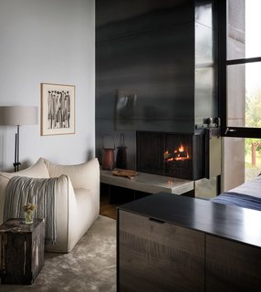 A vintage Mario Bellini club chair sits next to the hearth of the fireplace.