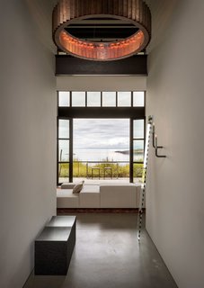 Upon entry, John Eric Byer's iconic block bench in blackened maple is revealed, adorned by a mirror piece, "Seeing Glass" by Sabine Marcelis and Brit van Nerven. And beyond, large openings display astounding views of the surroundings.