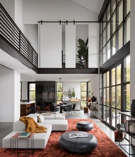 The upper floor wraps the main living space below, allowing for picturesque views from both levels of the home. Coffee bean tables by Holly Hunt sit atop a silk Tai Ping rust carpet, adjacent to a custom Living Divani Sofa.