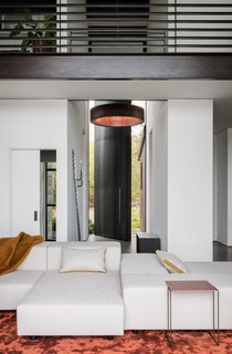 A 15-foot-tall, steel pivot entry door opens onto a combined art gallery and living space.