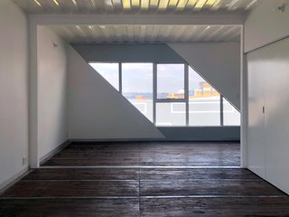 Interior spaces are minimal, carrying the simplistic design from outside to inside. Diagonal openings reveal snippets of the city.