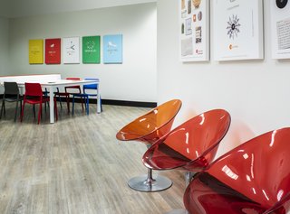 Bold colors in classic, modern furnishings create a fun work environment. Red and orange Kartell chairs, Modway dining chairs, and a stylish Ping Pong table by RS Barcelona combine to create an energetic, multi-functional space.