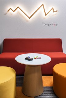 Throughout the space, the culture of the company is represented in the design. Here, a bolt LED Wall Sconce and wall graphic nicely highlight the brand. Pull up a seat on the bench or ottomans from BluDot, and start conceptualizing ideas on this writable table from Turnstone.