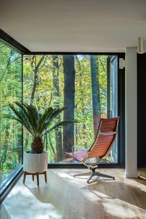 Glass corners create a seamless connection between the wooded landscape and interior living spaces.
