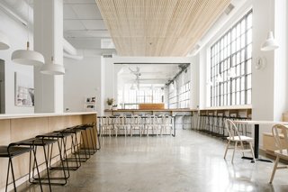 The open kitchen is the central hub of the office. It is a space to gather, take a break, and share ideas. Modern furnishings in molded black plywood and light ash tie in with the muted, industrial palette.