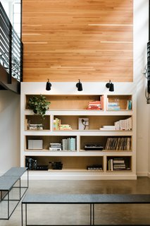Open to the story above, the library is filled with daylight—even though it is located on the lower level. A wood wall and custom built-ins draw warmth into the reading area.