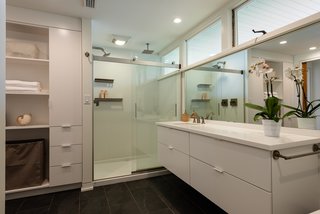 The updated bathrooms are clean and bright. A large mirror sits atop the custom floating vanity. Clerestory windows allow daylight to enter even the private spaces.