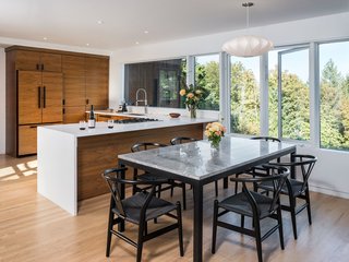 A George Nelson lamp hangs atop the marble dining room table. The open concept blends kitchen and dining as one.
