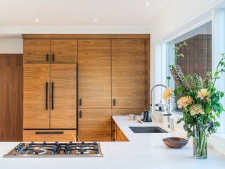 Walnut cabinets and crisp white countertops create a streamlined, modern kitchen.