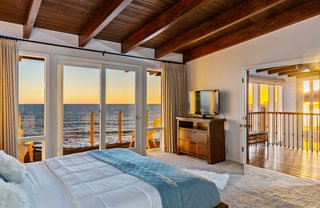 The master suite includes two private decks, a fireplace, large closet, updated bath, and wood-beamed ceiling. 