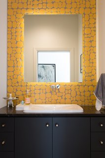This bright bathroom features Rox Solar yellow ceramic tile by Modwalls Rex Ray Studio, which provides a pop of color, a bit of texture, and a dose of fun.