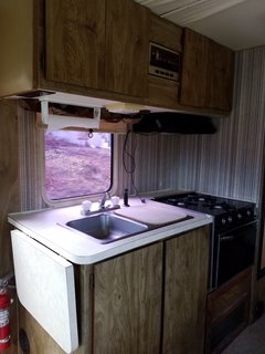 A Portland Couple Renovate a 1982 RV, Turning It Into Their New Home - Photo 8 of 12 - The RV's kitchen space before they stripped away the old wallpaper and updated the cabinetry.