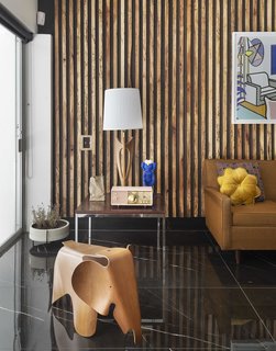 Florentino hired a local woodworker to create wood-paneled slated walls out of Angelique wood, mimicking a type of decor common in midcentury homes. The elephant stool is a cherrywood Eames: "It's one of my favorite things."