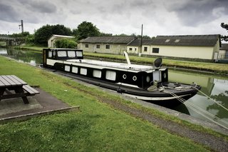 A New Book For Those Who Dream of Living in a Floating Home - Photo 8 of 11 - An old non-working Dutch barge from the 1930s was transformed into a home with modern-day luxuries like a gas stove, washer, dryer, and wood pellet-burning stove. Home to a roving photojournalist, the 59-foot-long by 14-foot-wide boat is split into four segments: a kitchen, dining nook, living room, and bedroom. 