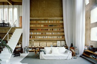 In the living room, ethereal white curtains soften the severity of the concrete walls.