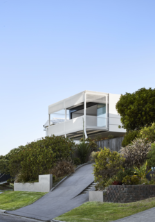Lush landscaping softens the steep driveway that leads to the garage at the base of the house.