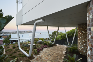 The top floor of the home is propped on three large steel supports that resembles paperclips.