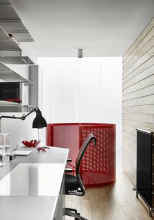 The home office is paneled in wood with perforated steel shelving. 