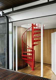 A red metal spiral staircase leads to the second-story office.