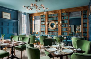 The Library, which serves as a dining room at the inn, was given a bold color scheme. The walls and paneling were painted in Farrow & Ball’s Stiffkey Blue, and the ceiling was given a lighter shade. The Dallas Chandelier from Arteriors adds a sleek, contemporary edge to the space. 