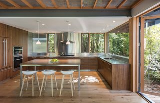 In the kitchen, custom walnut cabinets are paired with stainless-steel countertops and backsplash to help reflect the natural setting. "It captures the coloration of the landscape and the light, which makes it feel larger than it is," says Murdough. "Also, stainless steel is good for kitchens and work environments." 