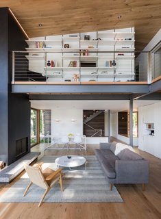In the lofted study, a Rakks modular shelf system was recessed into the drywall and topped with laminate boards. A white oak ceiling and flooring are found throughout the home, adding warmth to the minimalist palette. 