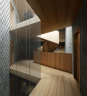 A wooden staircase contrasts with bare, concrete walls in Pilestredet P77.