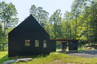The back of the home and gable ends are covered in blackened cedar.