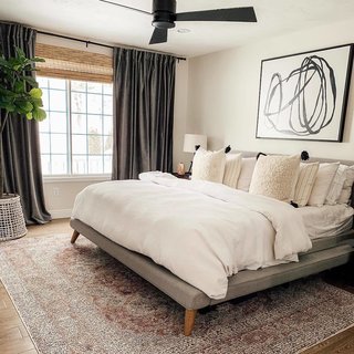 A fresh coat of paint, a new light fixture, and updated decor make all the difference. Julia placed a West Elm Mod Upholstered bed set over a Loloi Rugs Porcia PB-07 rug from Hayneedle. The bedroom is adorned with a Motion Lines 3 print from Anthropologie and worn velvet curtains from West Elm.