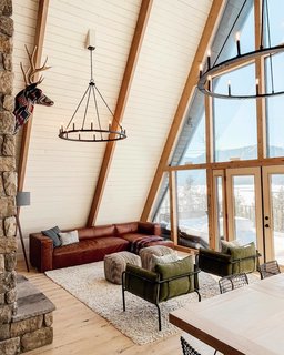 The living room in the cabin melds contemporary furnishings with rustic elements like the Capital Lighting 4912BI-000 Pearson chandeliers.