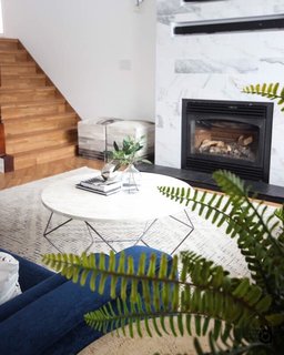 Neutrals surround an azure sofa with two Ashcroft poufs from Wayfair and an Origami coffee table and Stone Tile rug from West Elm.