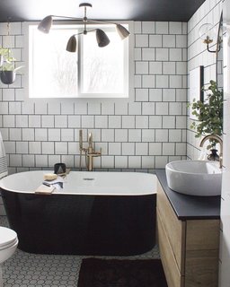 Two types of tile provide geometric texture against the inky soaking tub.