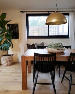 Conway's dining room is stylish but practical, pairing a Lexington dining table from Modern Komfort with Massey solid wood chairs from Wayfair. A Kathryn pedant light in brass hangs overhead, while a natural wood decorative bowl adds a touch of softness (both items are from Eclectic Goods). In the corner, a large macrame seagrass Bianca tote basket from World Market holds a fiddle-leaf fig tree.