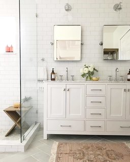 "For the master bathroom, I wanted to create a spa-like retreat for my husband and I. We chose classic finishes with gray herringbone floor tile, white subway tile for the walls, and chrome fixtures and hardware. We also took down a wall that separated the toilet and shower from the sink area and it made the bathroom feel twice as large."