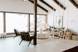 A West Elm Hamilton leather sofa offers comfy seating across from Cavett leather wood frame chairs from Crate & Barrel. Adding to the neutral palette is a jute boucle rug from West Elm and a swirled drum coffee table from Anthropologie.