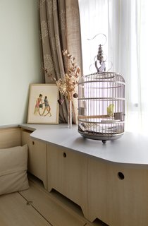 The extra wide cabinet top is specifically designed to hold the cage. Underneath lies extra seating for when the full dining table is rolled out of the kitchen cabinet. 