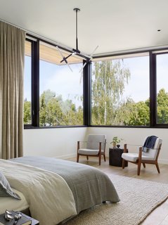 The airy second floor of the home opens up to treetops all around. Capo lounge chairs by Neri & Hu for De La Espada provide extra seating, while a Restoration Hardware rug and a Lindsey Adelman chandelier tie the room together. 
